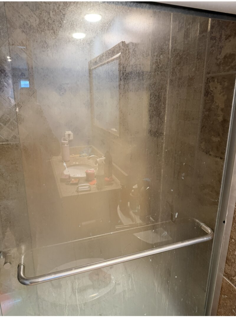 Shower before cleaning — hazy, water-spotted glass doors